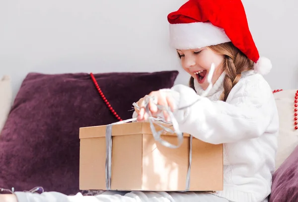 Una Chica Con Sombrero Santa Claus Sienta Sofá Desempaca Una —  Fotos de Stock