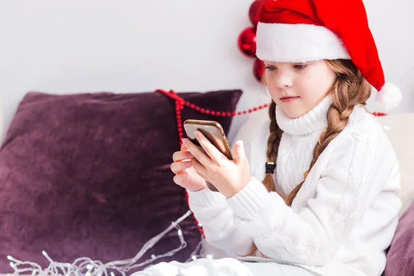 Una Niña Con Suéter Blanco Sombrero Santa Claus Mira Teléfono —  Fotos de Stock
