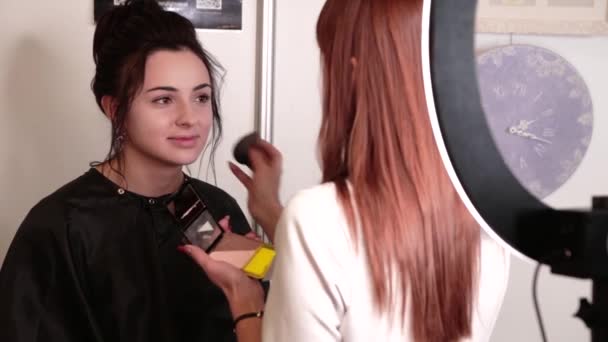 Stylist make-up kunstenaar maakt make-up aan een brunette meisje — Stockvideo
