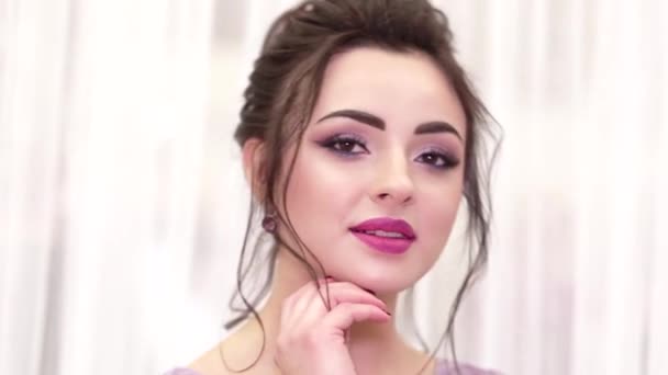 Barna lány gyönyörű smink és frizura pózol a kamera előtt egy lila ruha — Stock videók