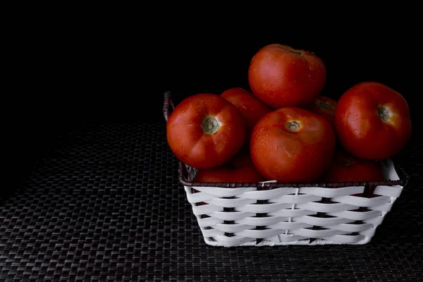 Frische Tomaten Auf Einem Teller Vor Dunklem Hintergrund Einen Korb — Stockfoto