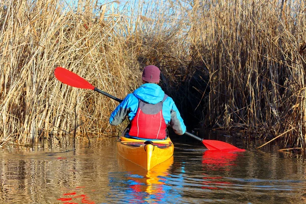 Açık bir sonbahar gününde kuru bir bastonla koridorda kürek çeken sarı kanolu bir adam.