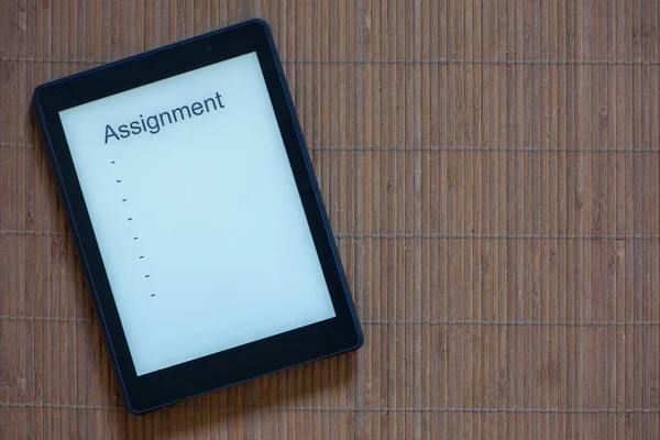 A black e-reader with white screen and text assignment