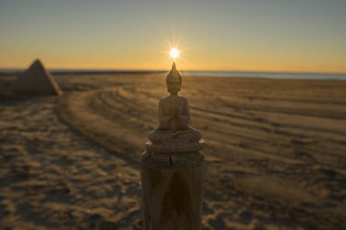 Deniz kenarında güzel bir gündoğumu meditasyon bir Buda figürü