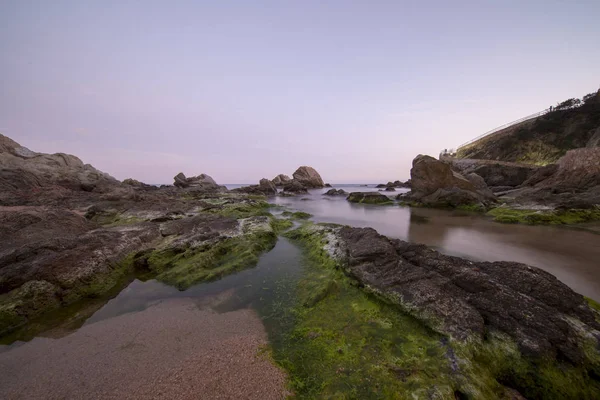 Lloret de Mar gün batımında plaj ve kayalar — Stok fotoğraf