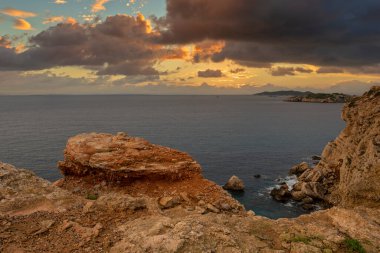 Güneşin doğuşunda İbiza kayalıkları olan sahil, İspanya