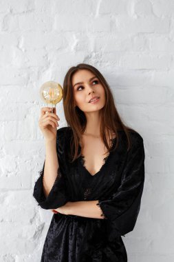 Elinde büyük bir ampul olan güzel bir genç kadın.