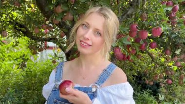 Elma tutan bir kadın. Bahçedeki Kadın. Elma bahçesinde meyve tutan ve gülümseyen bir kadın. Yüksek kaliteli FullHD görüntüler