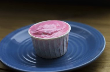 lezzetli muffin mavi plaka üzerinde pembe krema ile