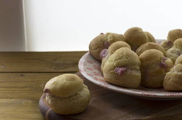 Leckere Eclairs Mit Rosa Creme Auf Teller Über Holzoberfläche — Stockfoto