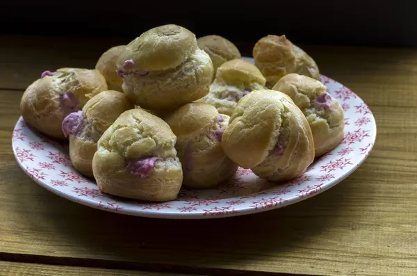 Leckere Eclairs Mit Rosa Creme Auf Teller Über Holzoberfläche — Stockfoto