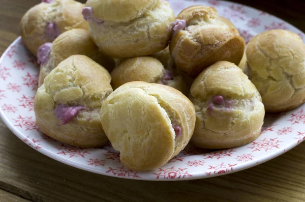 Leckere Eclairs Mit Rosa Creme Auf Teller Über Holzoberfläche — Stockfoto