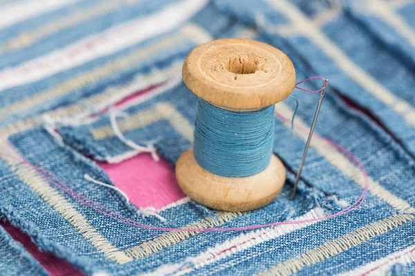 Concept de couture et de broderie - installation d'une aiguille et d'une bobine de fils bleus sur un tissu bleu décoré avec motif coupé, macro de couture et décors design en forme de labyrinthe . — Photo