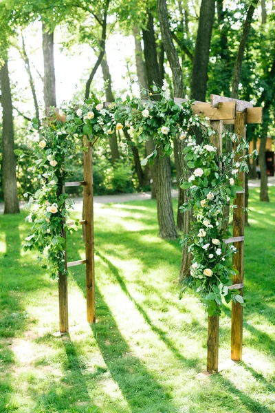 Morgen, Feier, Dekorationskonzept. Hochzeitsbogen in Form von Reifen für die Zeremonie dekoriert mit weißen Rosen und Nelken, die im zarten Licht der aufgehenden Frühlingssonne hervorstechen — Stockfoto