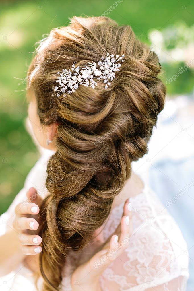 style, femininity, brides hairstyle concepr. in soft curly light brown hair of young woman there is shining barrette with diamonds in form of leaves and flowers