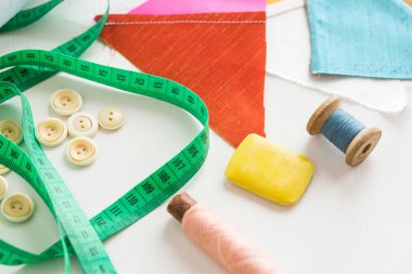 örgü işi, dikiş ve terzilik konsepti - yeşil ölçüm sayacına yakın çekim, beyaz düğmeler, bobinlerde mavi ve pembe iplik ve beyaz arka planda yamalar kesmek için sabun, üst görünüm, düz yatış