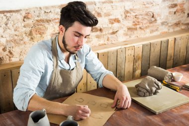 yakışıklı potter ware onun işyerinde kağıt üzerinde çizimler yapıyor. küçük işletme, el işi çalışmaları kavramı.