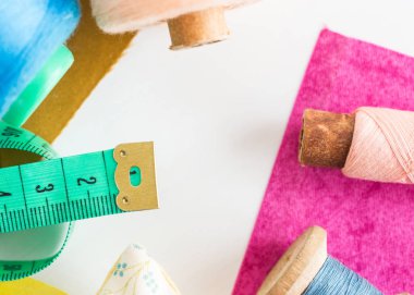 yama işi, dikiş ve terzilik konsepti - araçlara yakın çekim, ölçüm göstergesi, bobinlerdeki mavi ve pembe iplikler ve beyaz arka planda mor ve hardal rengi yamalar, üst görünüm, düz yatış