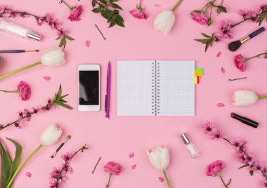 İş kadını, ofis, planlama konsepti. Pembe arka planın üst görüntüsü cep telefonu, küçük temiz planlayıcı, taze çiçekler ve kadın kozmetik ürünleri ve aksesuarları..