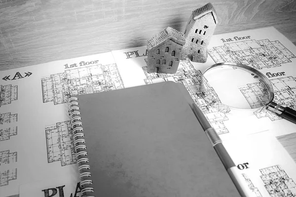 Drawings, paper, notebook and house layouts on the office desk. Construction, architecture, business.