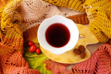 Masanın üzerinde sıcak kahve seramik kupa, bir kitap, rowan, briar ve akçaağaç yaprakları.