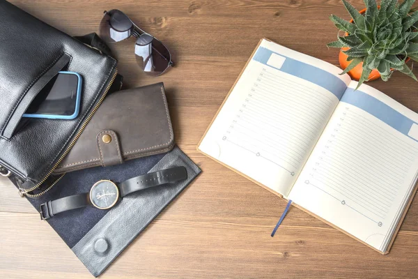 Men's accessories - a purse, glasses, a bag, a business card, a clock, car keys, a phone, a tablet, a notebook and a pen on the office desk. Business and finance. Lifestyle and fashion.