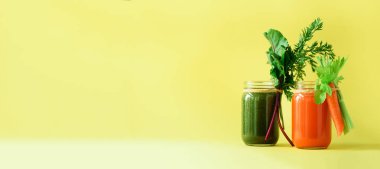 Sağlıklı organik yeşil ve turuncu smoothies sarı zemin üzerine. Afiş. Detoks içecekler cam sebze - havuç, kereviz, pancar Yeşiller ve başında gelen. Uzay kopyalayın. Yaz yiyecek konsepti