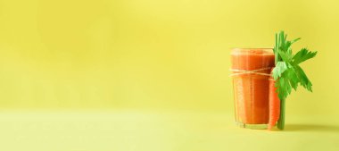 Organik havuç suyu ile havuç, kereviz sarı zemin üzerine. Cam taze sebze smothie. Afiş. Uzay kopyalayın. Yaz gıda kavramı. Yeme, alkali diyet sağlıklı detoks
