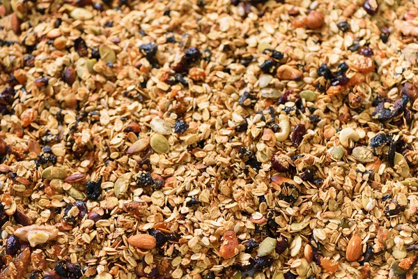 Biologische zelfgemaakte gebrande granola met noten en rozijnen op bakplaat. Eten als ontbijt. Maaltijden achtergrond, granola textuur — Stockfoto