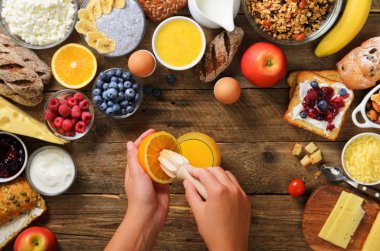 Turuncu meyve sıkma ve suyu yapım kadın. Yemek kahvaltı kız. Sağlıklı kahvaltı maddeler, gıda çerçeve. Granola, fındık, meyve, çilek, süt, yoğurt, meyve suyu, peynir. Üstten görünüm, kopya alanı