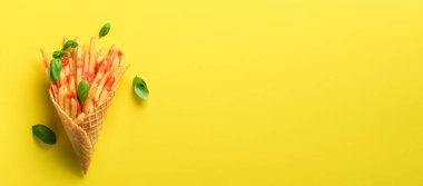 Gözleme koniler sarı zemin üzerine kızarmış patates. Sıcak tuzlu patates kızartması sos ile. Afiş. Fast food, abur cubur, diyet kavramı. Üstten görünüm. En az tarzı. Pop sanat tasarım, yaratıcı kavramı