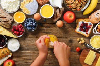 Turuncu meyve sıkma ve suyu yapım kadın. Yemek kahvaltı kız. Sağlıklı kahvaltı maddeler, gıda çerçeve. Granola, fındık, meyve, çilek, süt, yoğurt, meyve suyu, peynir. Üstten görünüm, kopya alanı
