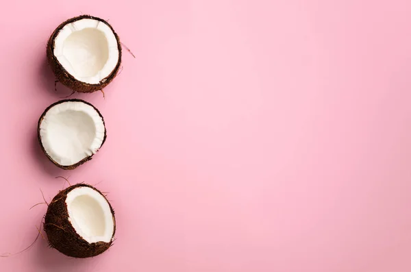Muster mit reifen Kokosnüssen auf rosa Hintergrund. Ansicht von oben. Kopierraum. Pop Art Design, kreatives Sommerkonzept. Hälfte Kokosnuss im minimalen flachen Lay-Stil. — Stockfoto