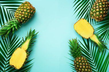 Ananas ve tropikal palmiye yaprakları punchy pastel turkuaz arka plan üzerinde. Yaz konsepti. Yaratıcı düz kopya alanı ile yatıyordu. Üstten görünüm