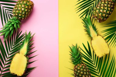 Ananas, palmiye yaprakları kopya alanı pastel renkli pembe ve sarı zemin üzerine. Yaratıcı yaz konsepti. Düz lat, üstten görünüm