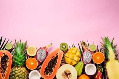 Egzotik meyve ve tropikal palmiye yaprakları üzerinde pastel pembe arka plan - papaya, mango, ananas, muz, carambola, dragon meyve, kivi, limon, portakal, kavun, Hindistan cevizi, kireç. Üstten görünüm.