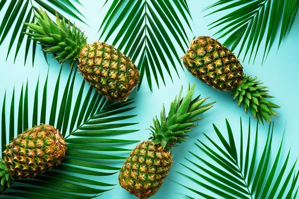 Ananas en tropische palm bladeren op pastel turquoise achtergrond. Zomer concept. Creatieve platte alay met kopie ruimte. Bovenaanzicht — Stockfoto