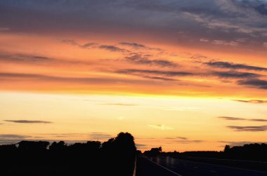 Boş asfalt yol ve manzarası üzerinde yükselen güneş. Yol üzerinde renkli gün batımı. Minimalist tarzı tasarım. Doğa arka plan, yatay, kopya alanı. Afiş