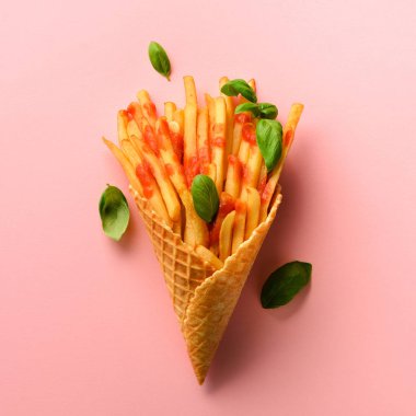 Gözleme koniler pembe bir arka plan üzerinde kızarmış patates. Sıcak tuzlu patates kızartması sosu, fesleğen yaprağı. Fast food, abur cubur, diyet kavramı. Üstten Görünüm. En az tarzı. Pop sanat tasarım, yaratıcı kavramı