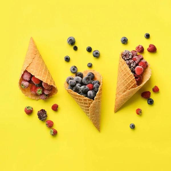 Frozen berries - strawberry, blueberry, blackberry, raspberry in waffle cones on yellow background. Top view. Banner. Pattern for minimal style. Pop art design, creative concept — Stock Photo, Image