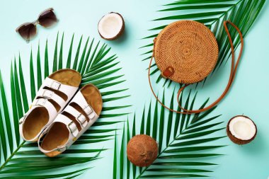 Rattan çanta, Hindistan cevizi, birkenstocks, hurma dalları güneş gözlüğü üzerinde arka plan mavi. Afiş. Üstten görünüm kopya alanı ile. Trendy bambu çanta ve ayakkabılar. Yaz moda düz yatıyordu. Gezi, tatil kavramı