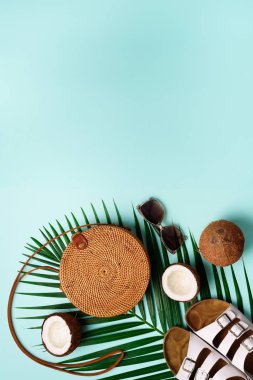 Rattan çanta, Hindistan cevizi, birkenstocks, hurma dalları güneş gözlüğü üzerinde arka plan mavi. Afiş. Üstten görünüm kopya alanı ile. Trendy bambu çanta ve ayakkabılar. Yaz moda düz yatıyordu. Gezi, tatil kavramı