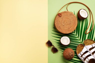 Şık rattan çanta, Hindistan cevizi, birkenstocks, hurma dalları, zeytin yeşil arka plan üzerinde güneş gözlüğü. Afiş. Üstten görünüm kopya alanı ile. Trendy bambu çanta ve beyaz ayakkabı. Yaz moda düz yatıyordu