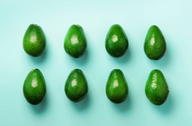 Mavi zemin üzerine yeşil avokado desen. Üstten görünüm. Pop sanat tasarım, yaratıcı yaz gıda kavramı. Organik avocadoes en az daire yatıyordu tarzı.