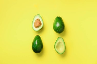 Organik avokado tohumu, avokado yarısı ve sarı zemin üzerine tüm meyve ile. Üstten görünüm. Pop sanat tasarım, yaratıcı yaz gıda kavramı. Yeşil avocadoes desen en az daire yatıyordu tarzı.