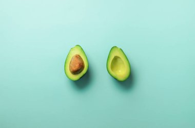 Yeşil Avokado tohum pastel mavi arka plan ile yarıya indirir. Yaratıcı en az düz stil kopya alanı ile yatıyordu. Yaz gıda kavramı. Üstten görünüm. Pop sanat tasarım.