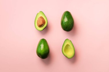 Organik avokado tohumu, avokado yarısı ve pembe bir arka plan üzerinde tüm meyve ile. Üstten görünüm. Pop sanat tasarım, yaratıcı yaz gıda kavramı. Yeşil avocadoes desen en az daire yatıyordu tarzı.