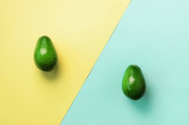 Avokado tohum, meyve mavi ve sarı zemin üzerine dilimlenmiş. Üstten görünüm. Pop sanat tasarım, yaratıcı yaz gıda kavramı. En az düz stil yatıyordu.