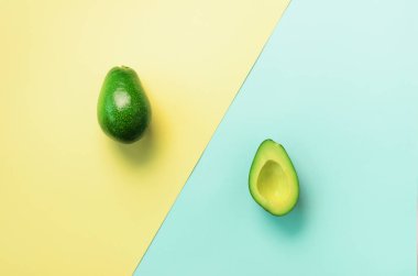 Avokado tohum, meyve mavi ve sarı zemin üzerine dilimlenmiş. Üstten görünüm. Pop sanat tasarım, yaratıcı yaz gıda kavramı. En az düz stil yatıyordu.