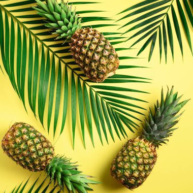 Ananas ve tropikal palmiye yaprakları sarı arka plan üzerinde. Üstten görünüm. Yaz konsepti. Yaratıcı düz lay kopya alanı ile.